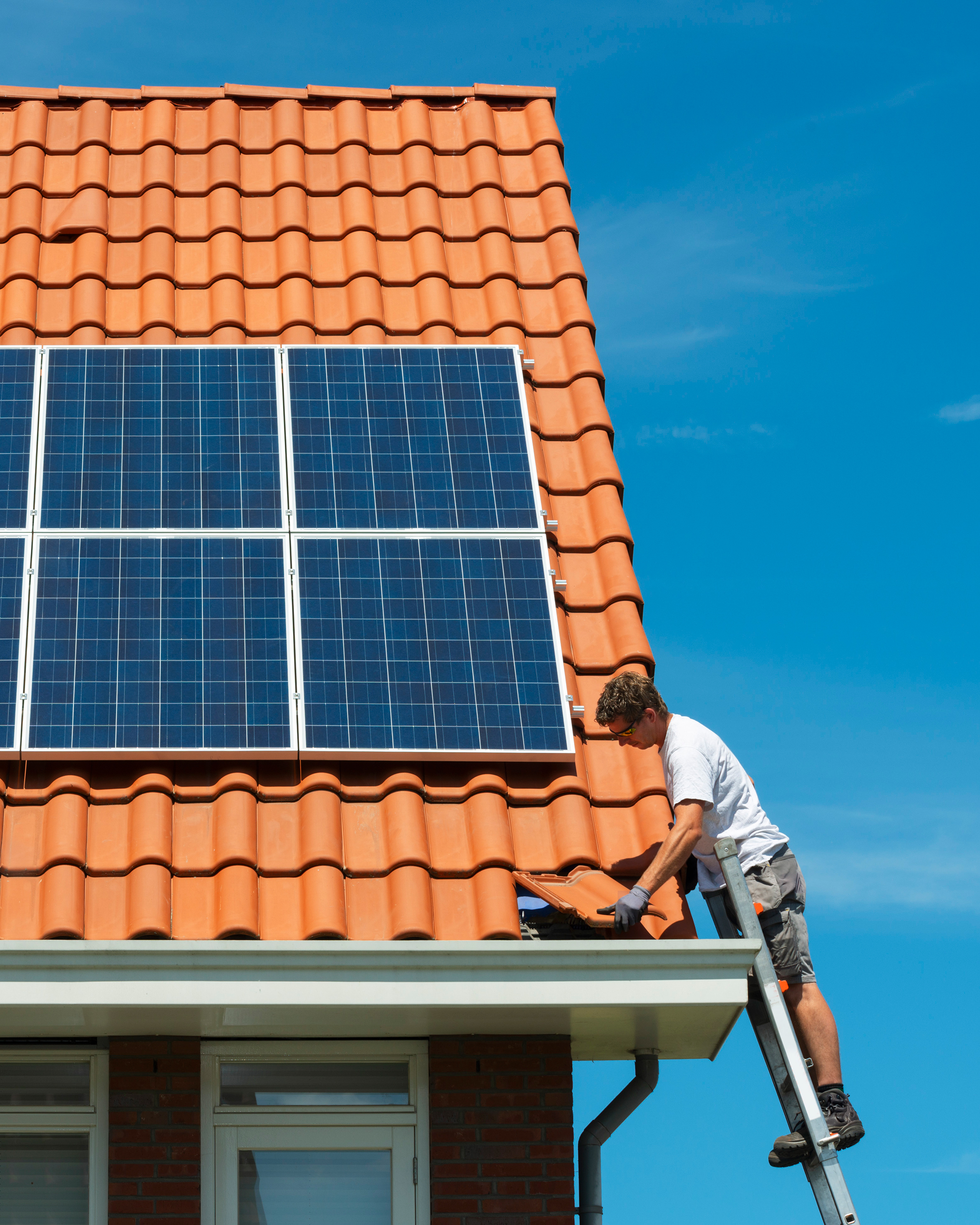 glove,solar panels,housing,roof,adult,male,man,person,worker,shoe