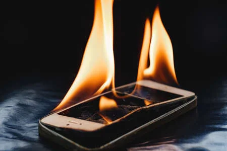 176475059-burning-broken-smartphone-on-a-black-background.webp