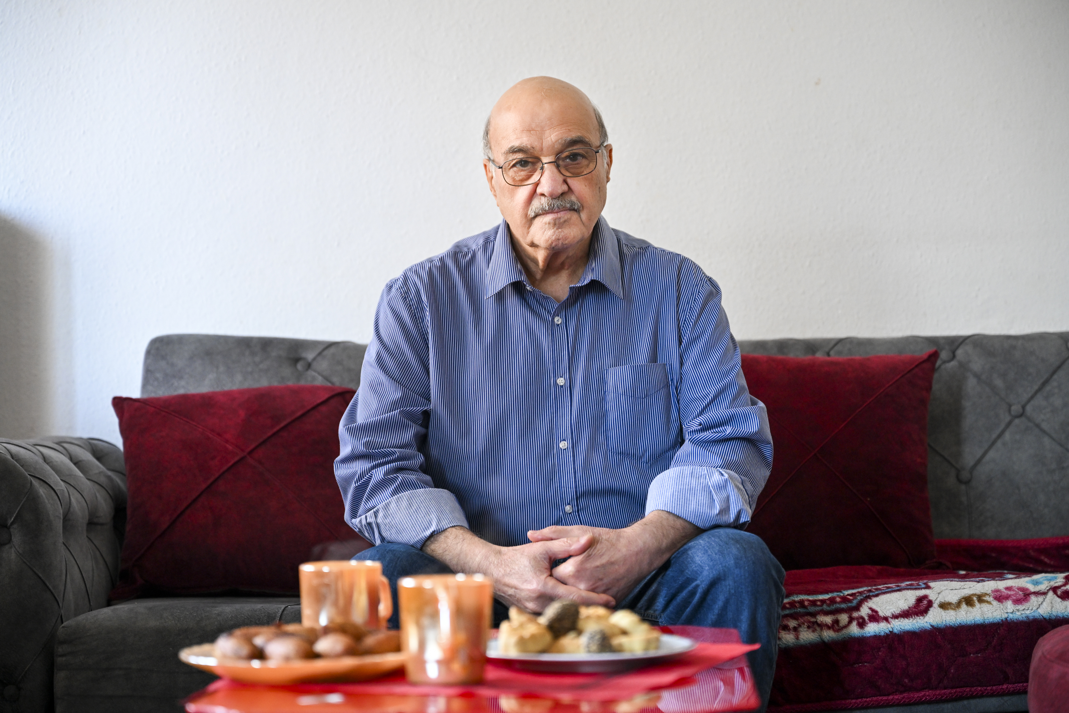 couch,furniture,adult,male,man,person,sitting,glasses,senior citizen,cup